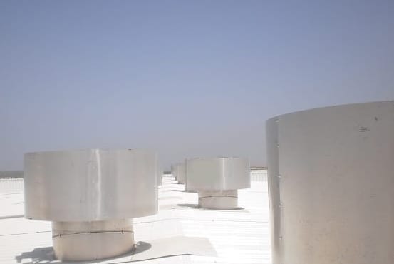 Hurricane Plus static wind induced ventilator on the roof of an industrial building with a hazy sky