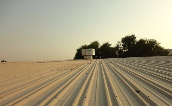Industrial roof with a Hurricane® Plus ventilator and trees in the background