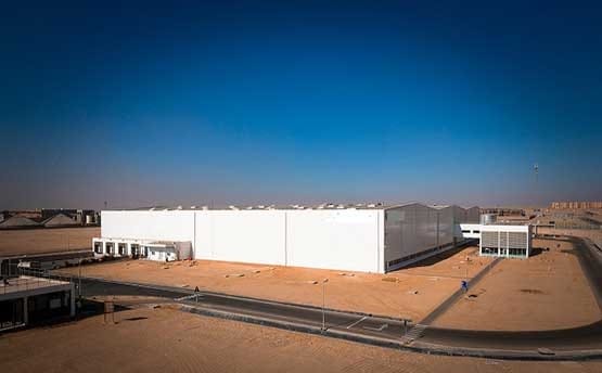 Wide angle shot of Grand Mills' white industrial building in the desert with Hurricane® Plus ventilators on the roof